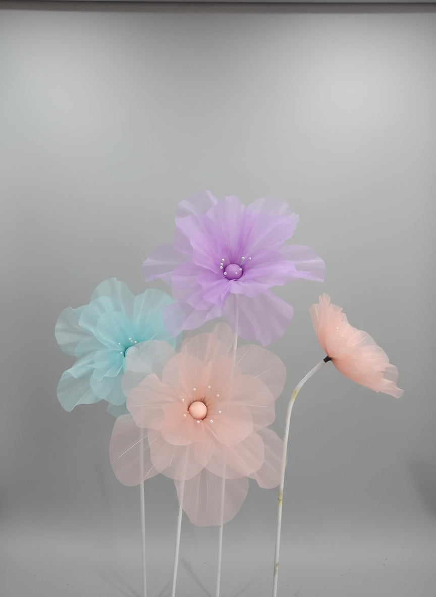 Decorative flowers on stands with colorful tassels and beads in the background.